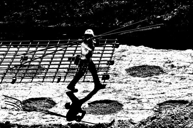 Steel worker carrying steel rods in construction site