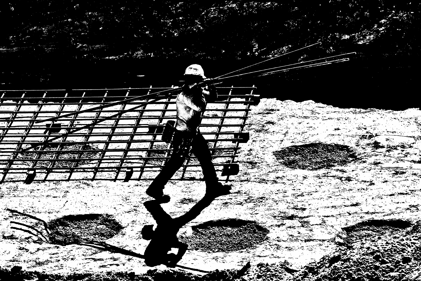 Steel worker carrying steel rods in construction site